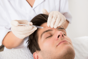 man with eyes closed receiving forehead botox injections