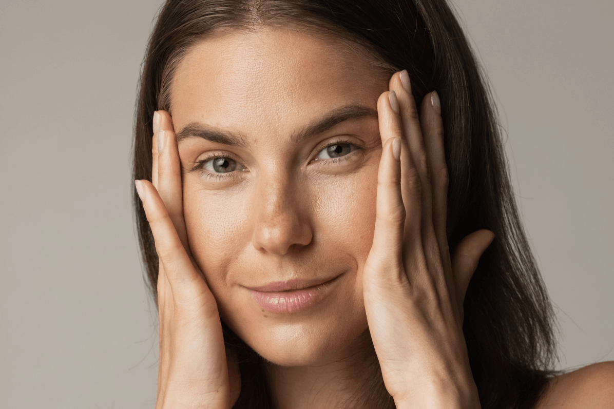 woman with her palms on each side of her face pulling her skin back slightly