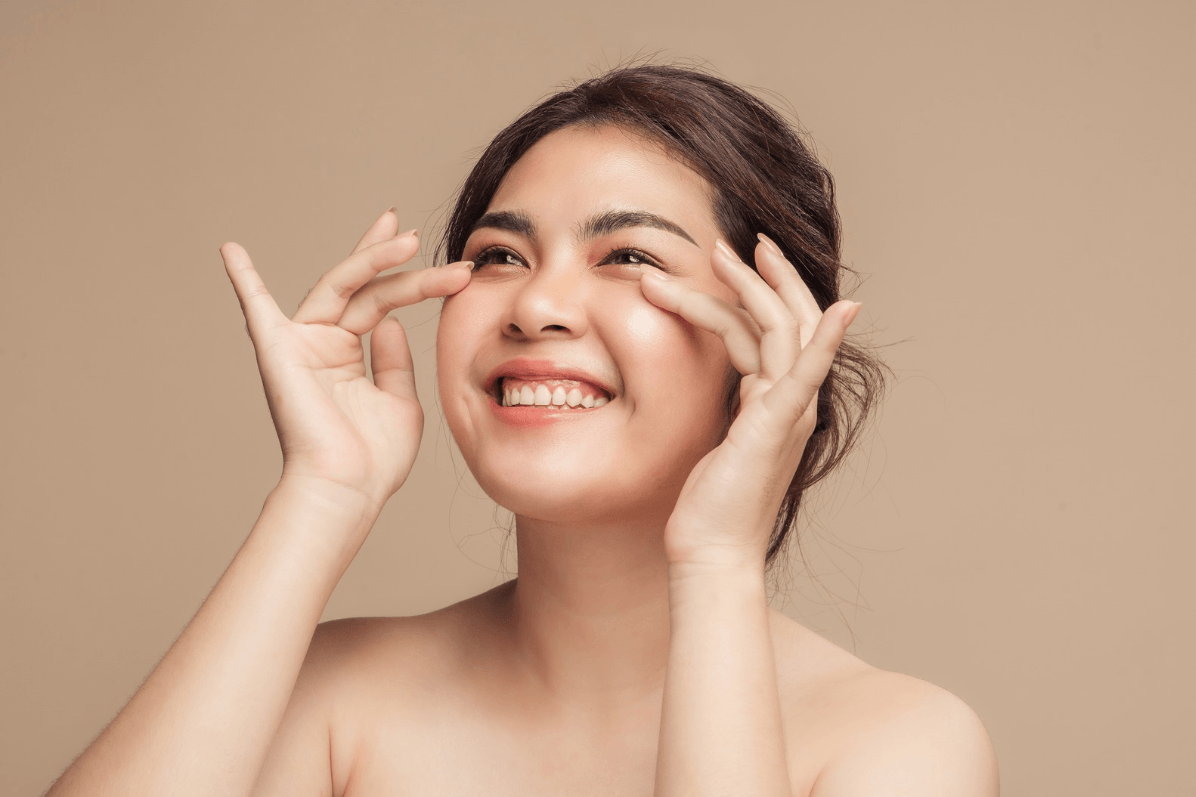 woman smiling away from the camera and putting her fingers under her eyes